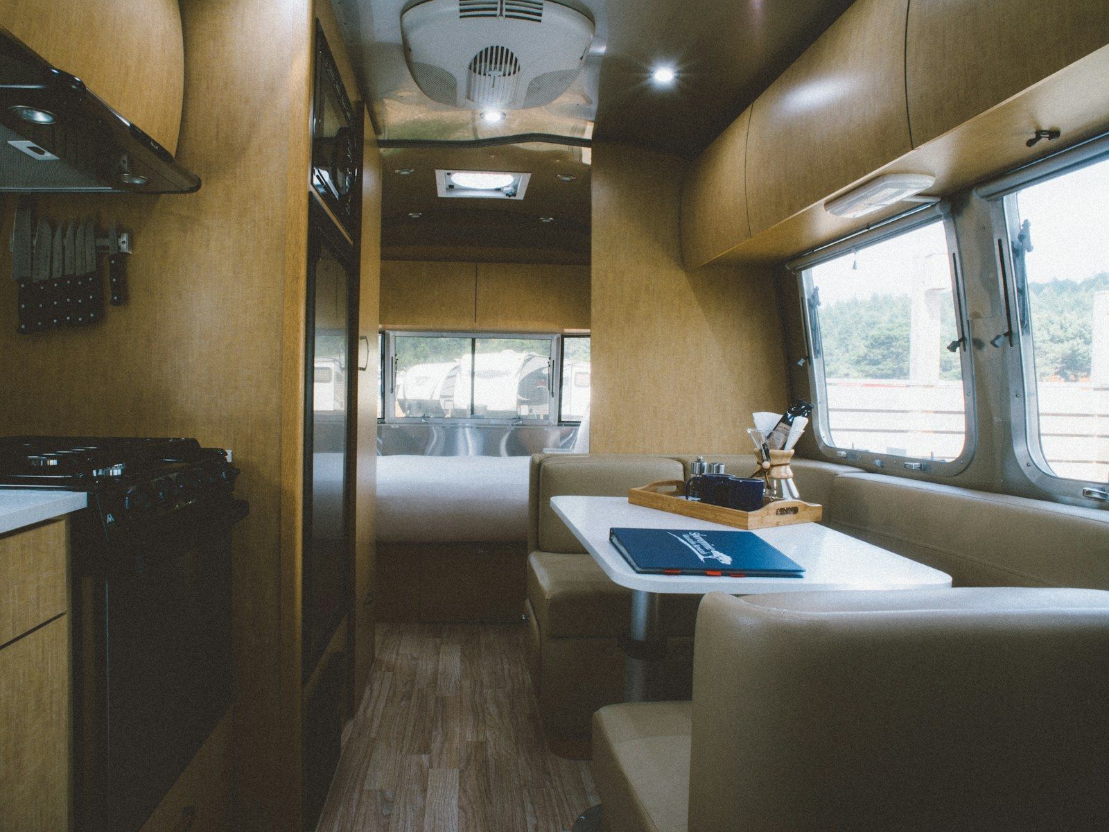 Intérieur d’hébergement mobile : cuisine en bois et coin repas avec banquette